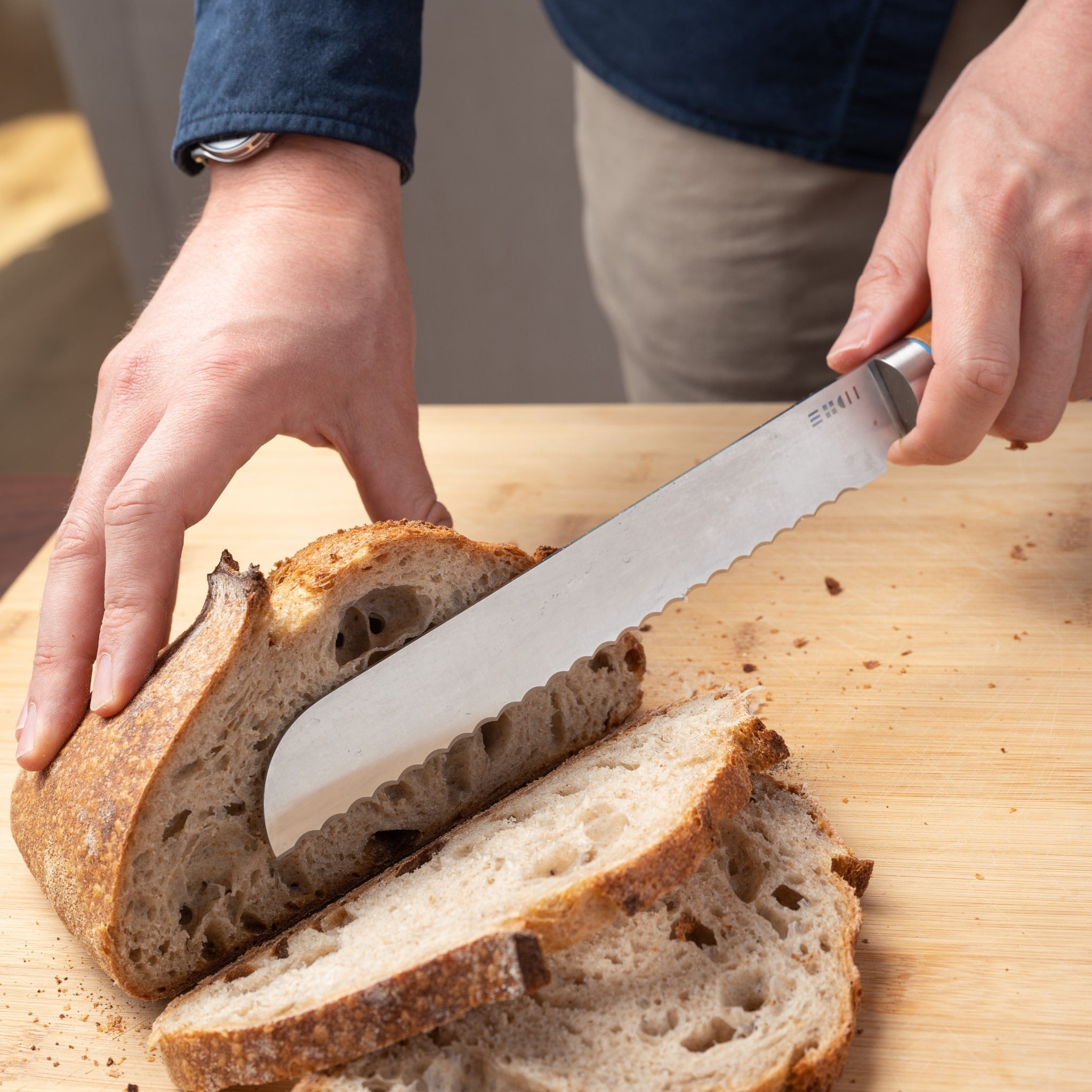 Couteau à pain ETCH découpant une miche croustillante, lame crantée pour une coupe sans écrasement