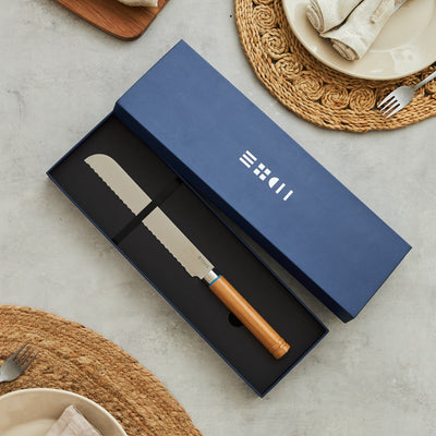 Couteau à pain ETCH présenté dans un coffret cadeau bleu marine profond, lame dentelée 22 cm et manche bois aux nervures naturelles
