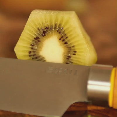Vidéo macro du couteau éminceur ETCH tranchant un kiwi avec précision, sans écraser la pulpe ni déraper sur la peau