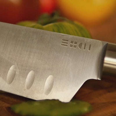 Vidéo macro du couteau Santoku ETCH tranchant une tomate verte avec précision, lame alvéolée et coupe nette en gros plan