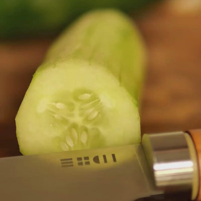 Vidéo macro du couteau de chef ETCH coupant une rondelle de concombre avec précision, lame lisse en action tranchante